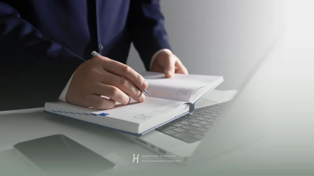 professional reviewing planner over laptop, illustrating scheduling conflicts and inefficiencies in executive calendar management