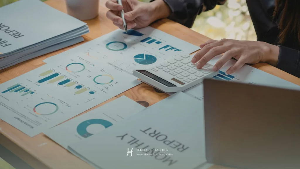 Analyst reviewing financial charts and using calculator for salary and bonus benchmarking in a family office