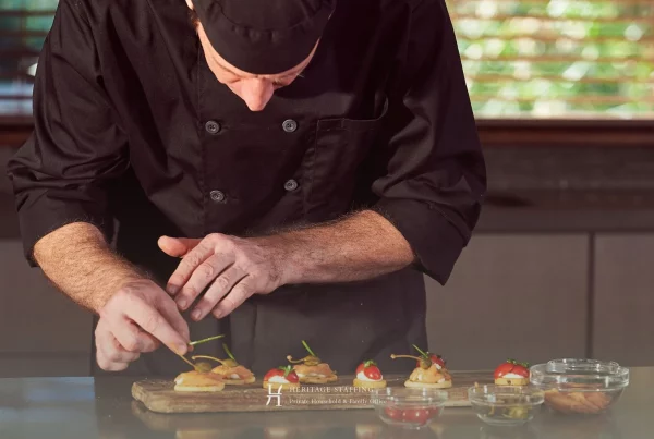 Private chef carefully plating gourmet canapés in a luxury residential kitchen, reflecting food safety liability management in family offices.