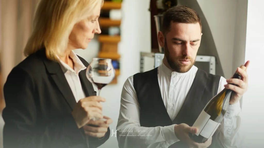 Sommelier and estate manager reviewing a wine bottle label during inventory control in a private collection
